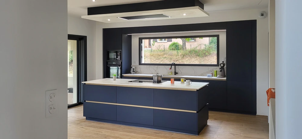 Cuisine moderne équipée avec îlot central, électroménager intégré en acier inoxydable, crédence en carrelage métro blanc