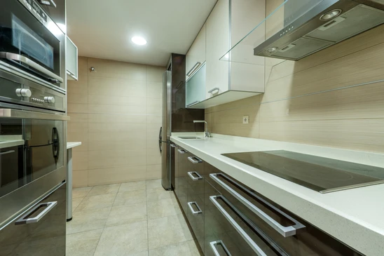 Cuisine moderne avec &eacute;vier encastr&eacute; noir mat de forme rectangulaire, robinet mitigeur noir &agrave; bec haut pivotant